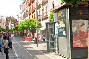 Un kiosco con publicidad en una calle llena de gente