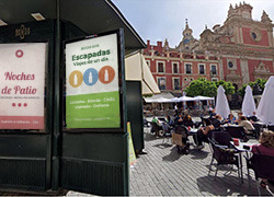 Un kiosco con publicidad junto a mesas con gente