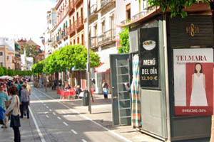 Kiosco con publicidad en la calle San Jacinto, llena de gente